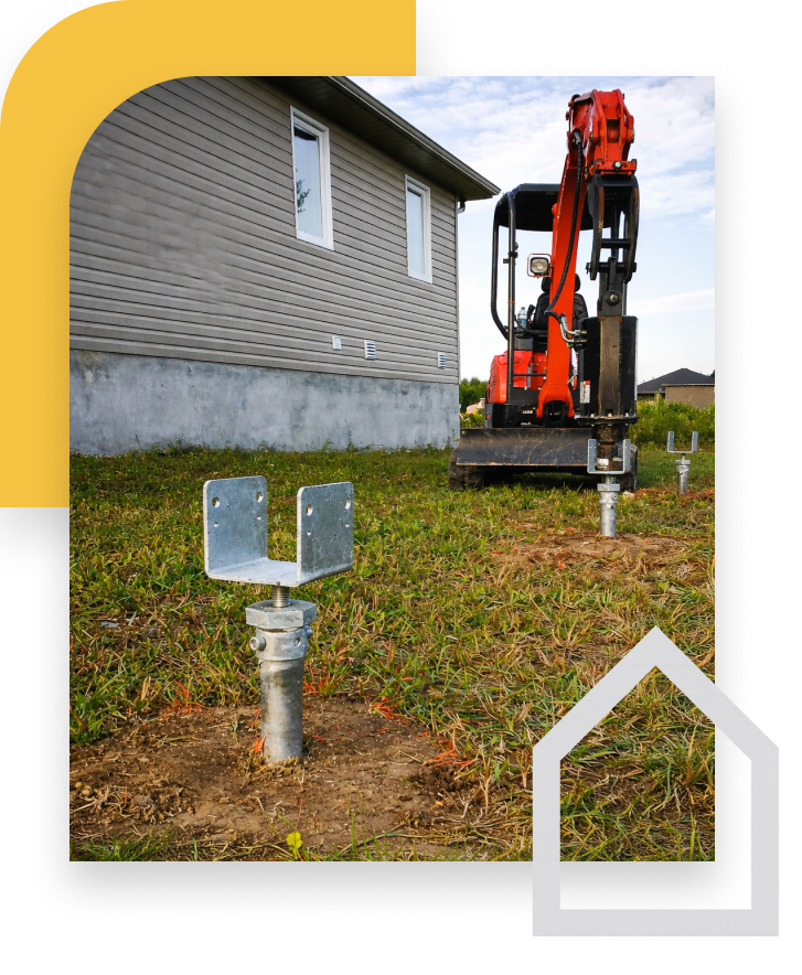 screw piles in ground with grey house